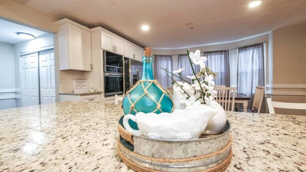A kitchen with white cabinets, a granite countertop, and a dining area with a table and chairs.