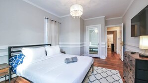 A hotel room with a bed, bedside tables, a chandelier, a wardrobe, and a mirror.