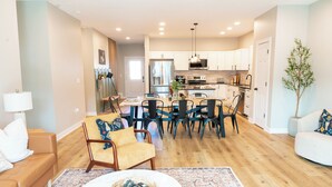 A modern living room with a sofa, coffee table, and dining area with chairs and a table.