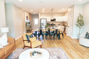 A modern living room with a sofa, coffee table, and dining area with chairs and a table. - NEW Springmill Escape in Westfield - 2 king beds, office, fenced yard and more (Westfield)