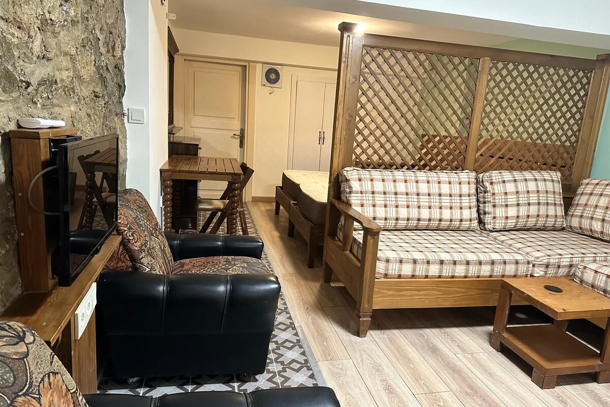 A living room with a sofa set, a coffee table, a TV, and a patterned rug.