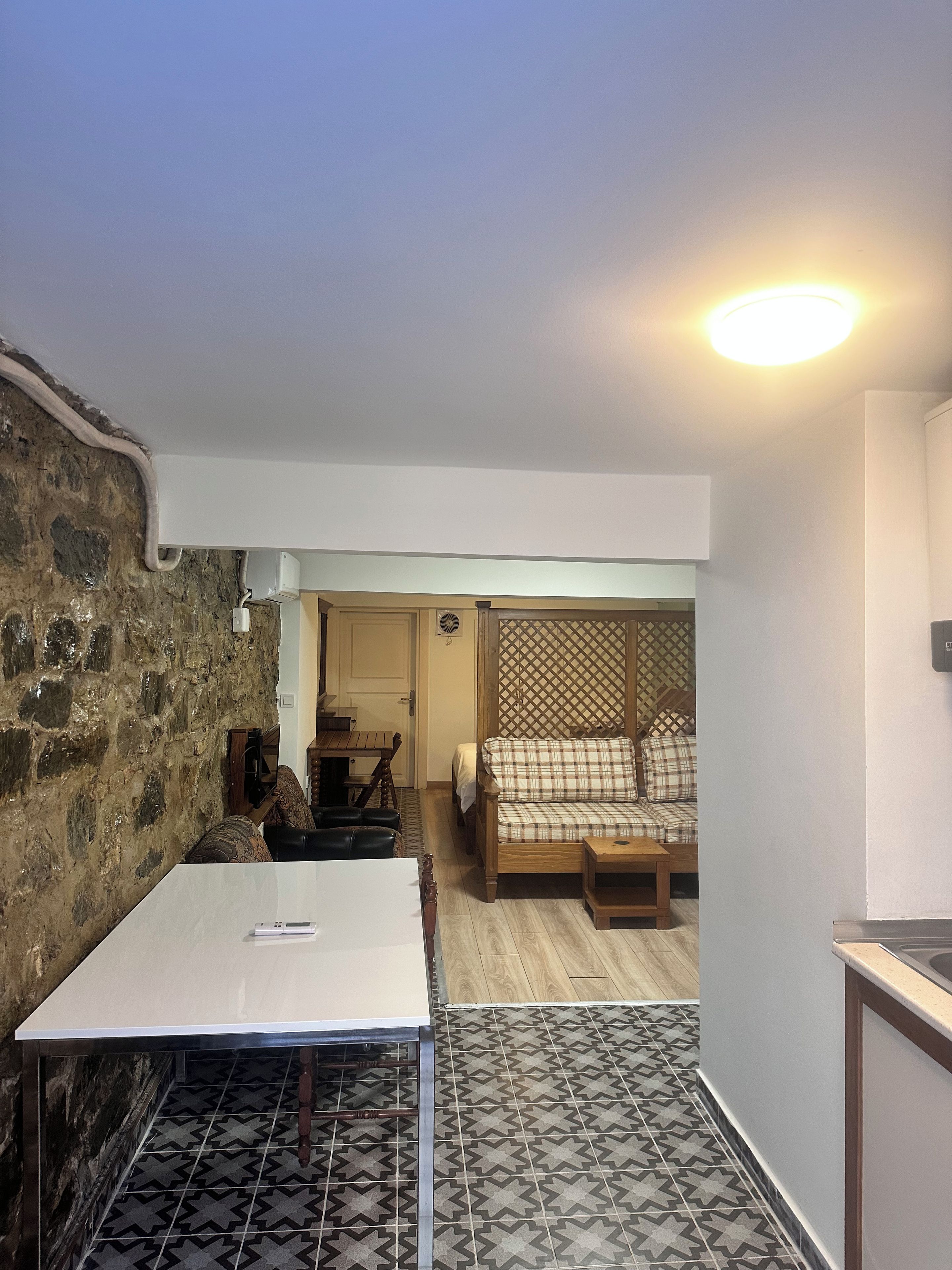 Une pièce compacte comprenant un coin cuisine, un espace repas et un coin salon avec un canapé et un mur décoré de motifs.