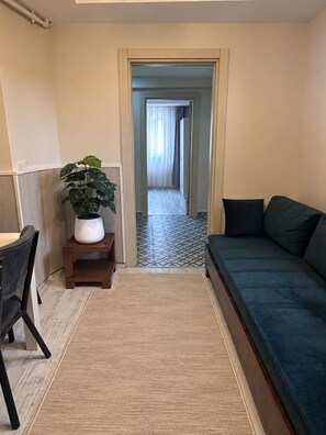 A compact living space with a sofa, a small table, a chair, a potted plant, and a tiled floor. - Taksim cozy apartments (Istanbul)