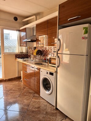 A modern kitchen with a built-in washing machine, stainless steel appliances, and wooden cabinets. - Taksim cozy apartments (Istanbul)