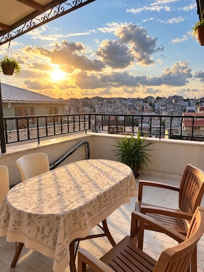 A balcony with a table and chairs, overlooking a cityscape during sunset. - Taksim cozy apartments (Istanbul)
