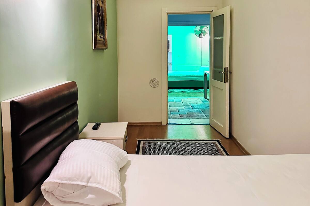 Een hotelkamer met een bed, nachtkastje en een wandlamp.