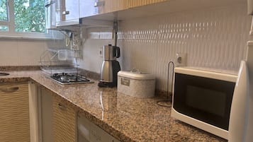 Une cuisine moderne équipée d’un lave-linge intégré, d’une machine à café et d’un four à micro-ondes.