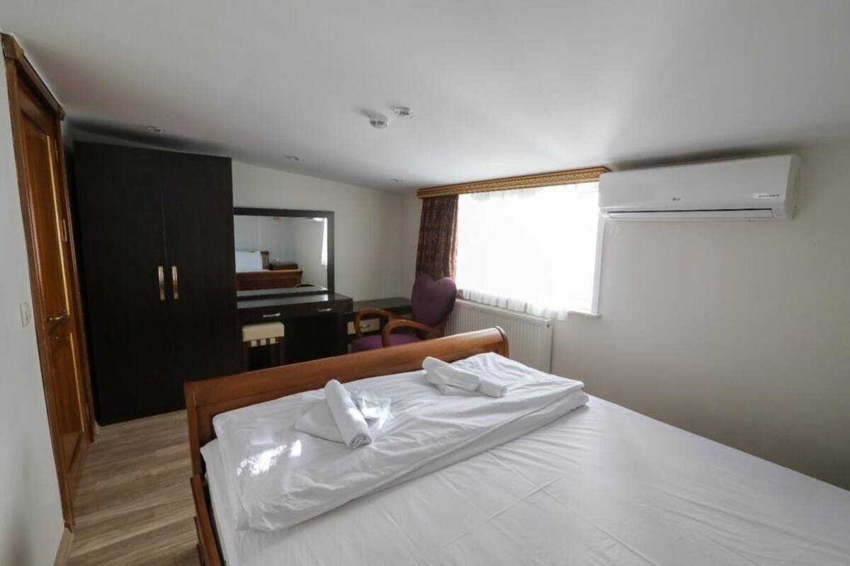 Een hotelkamer met een bed, bureau, stoel, kledingkast en airconditioning.