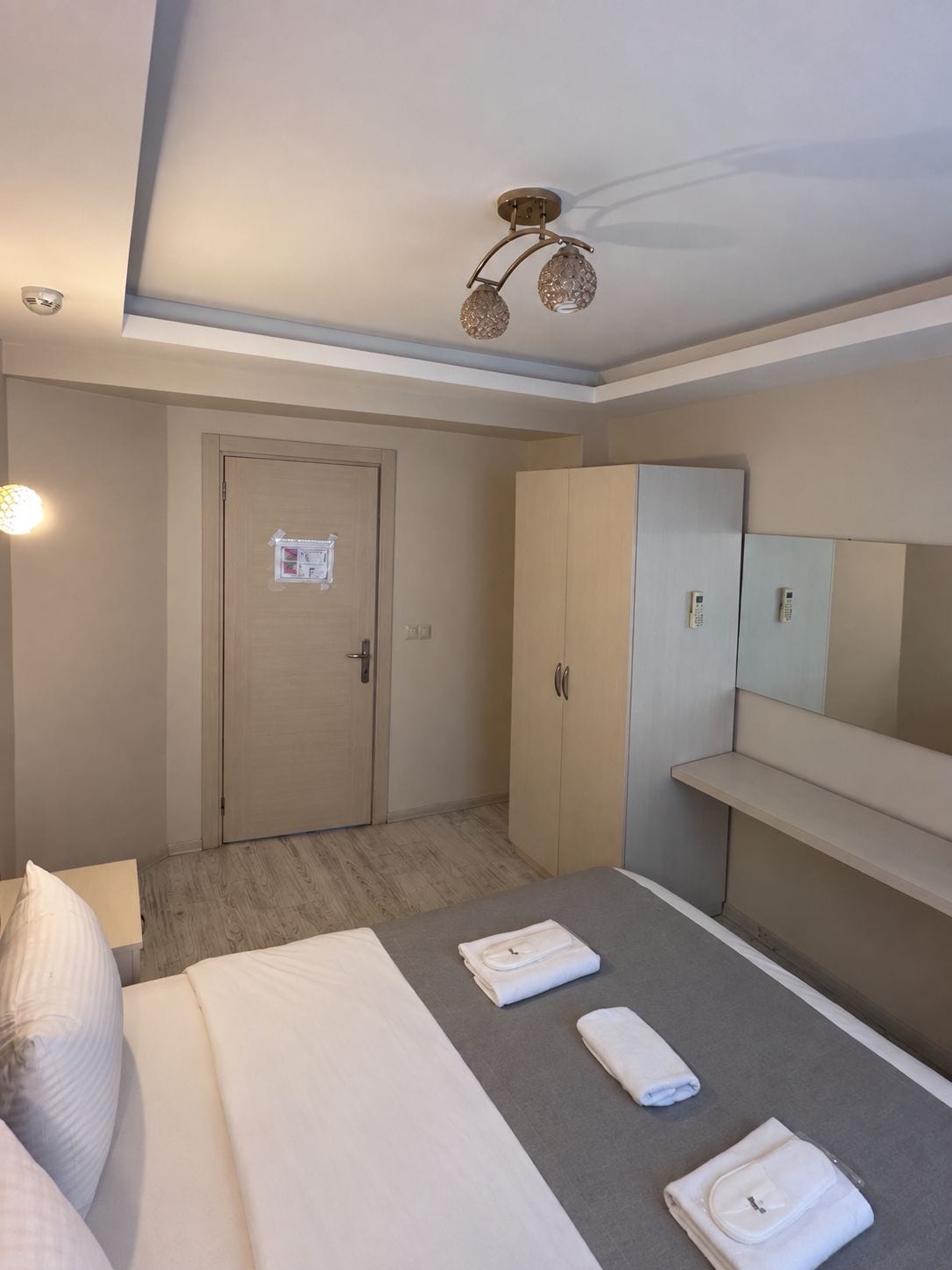 Une chambre d’hôtel équipée d’un lit, d’une armoire, d’un miroir et d’un luminaire au plafond.