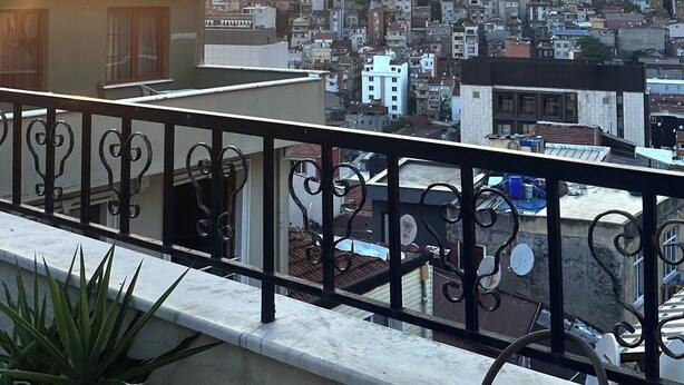 A balcony with a metal railing overlooking a cityscape during sunset. - Taksim cozy apartments (Istanbul)