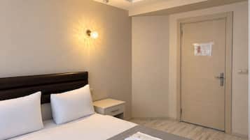 Une chambre d’hôtel avec un grand lit, des tables de chevet, une armoire et un luminaire au plafond.