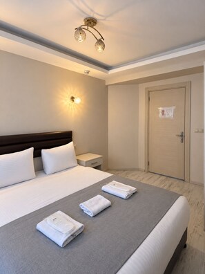 A hotel room with a large bed, bedside tables, a wardrobe, and a ceiling light fixture. - Taksim cozy apartments (Istanbul)