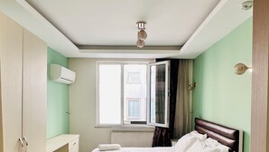 A neatly arranged bedroom with a bed, bedside tables, and a window with curtains. - Taksim cozy apartments (Istanbul)