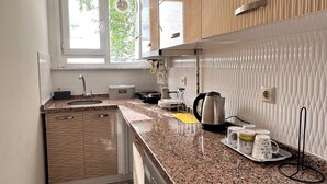 A modern kitchen with a granite countertop, built-in appliances, and a window with a view of greenery. - Taksim cozy apartments (Istanbul)