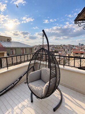A hanging chair on a balcony with a city view. - Taksim cozy apartments (Istanbul)