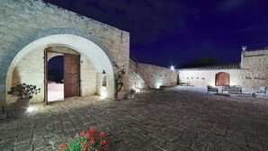A stone courtyard with an arched doorway, a bench, and a potted plant. - Scifazzo, ancient Sicilian villa with pool (Ragusa)