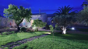 A well-maintained garden with a stone wall, a pathway, and a building with a visible chimney. - Scifazzo, ancient Sicilian villa with pool (Ragusa)