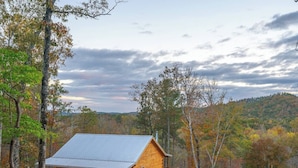 A wooden cabin with a metal roof, surrounded by trees and a hilly landscape. - Pinhoti Ridge Retreat Cabin 1, Pinhoti Path (Talladega)