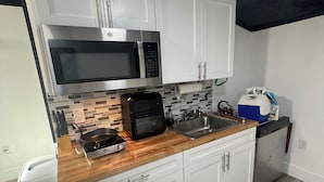 Una cocina moderna con armarios blancos, un microondas de acero inoxidable, un tostador y un lavavajillas.