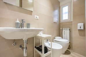 A bathroom with a sink, toilet, and a window.
