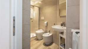 Un baño moderno con ducha, inodoro, bidé, lavamanos y tendedero para toallas.