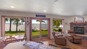 A dining area with a table and chairs, a fireplace, and a view of a lake through glass doors. - Relaxing Lakefront Cottage, Kayaks, Bikes, Fishing (Sturgeon Bay)