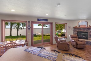 A dining area with a table and chairs, a fireplace, and a view of a lake through glass doors.