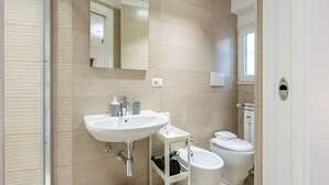 Un baño equipado con lavamanos, espejo, inodoro, bidé y zona de ducha.