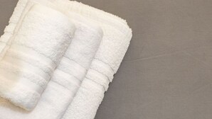 Una toalla blanca doblada con cuidado sobre una superficie gris.