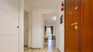 A hallway with a wooden door, a white wall with a number, and a window with curtains. - Ostiense Flat&Rooms - Double Room by Rentbeat (Roma)