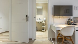 A modern room with a desk, chair, TV, and a bathroom visible through an open door. - Ostiense Flat&Rooms - Double Room by Rentbeat (Roma)