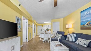 A living room with a TV, sofa, and dining area. - Oceanfront | Heated Pools + Hot Tub | King | W/D | Cable (Orange Beach)