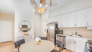 A modern kitchen with white cabinets, a stainless steel refrigerator, and a round dining table with grey chairs. - Lux Penthouse~King Beds~Workspaces~Parking~ Near Zoo, Balboa Park! (San Diego)