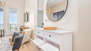 A modern bathroom with a white vanity, a round mirror, and a large window. - Lux Penthouse~King Beds~Workspaces~Parking~ Near Zoo, Balboa Park! (San Diego)