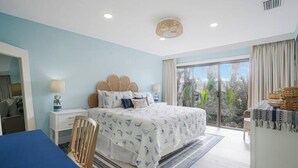 A bedroom with a bed, a desk, and a chair. There is a window with a view of trees. - Sand & Sea Oasis: Condo with Private Beach Access (Holmes Beach)