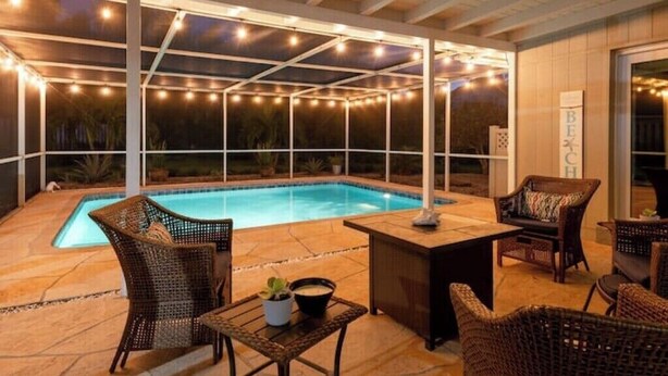 An outdoor pool area with wicker furniture and string lights. - Coastal Oasis: Cheerful 3Bedroom, Pool, Large Yard (Bradenton)