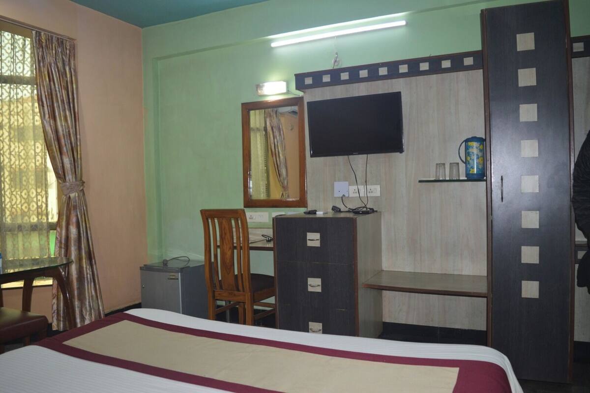A room with a bed, a desk, a chair, a television, and a wardrobe.