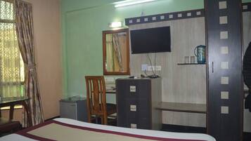 A room with a bed, a desk, a chair, a television, and a wardrobe.