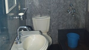 Et badeværelse med toilet, håndvask og en blå balje.