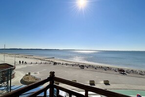 Uma praia com céu claro, sol e vista para o mar.