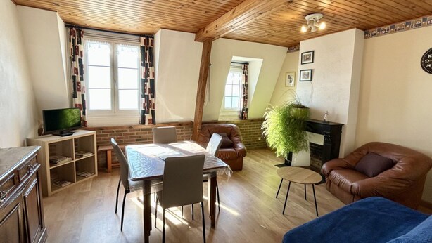 Una sala de estar acogedora con una mesa de comedor, sillones de cuero, televisor, chimenea y una planta grande.
