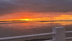 Un atardecer sobre una masa de agua con una barandilla al frente.