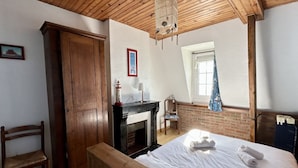 Un dormitorio con una cama de madera, una chimenea, un armario de madera y una ventana con vistas.