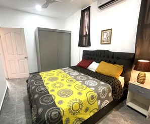 Un dormitorio con cama, mesita de noche, lámpara, puerta y aire acondicionado.