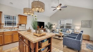 A spacious living area with a kitchen, a dining table, and a blue armchair. - Charming Coastal Cottage on St. Simons Island (St. Simons Island)
