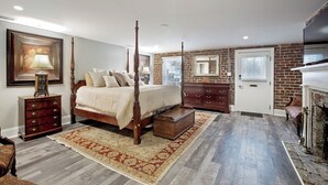 Ein Schlafzimmer mit Himmelbett, Schminktisch, Nachttisch, Spiegel und Kamin.