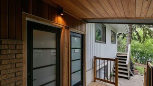 A wooden exterior with a glass door and a wooden staircase leading to a covered porch. - No. 1 Rosetree Suites - 3 Beds - Perfect Family Location in Calgary (Calgary)