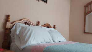A bed with a wooden headboard, white pillows, and a quilted bedspread. - Lonko Hostel Arequipa (Arequipa)