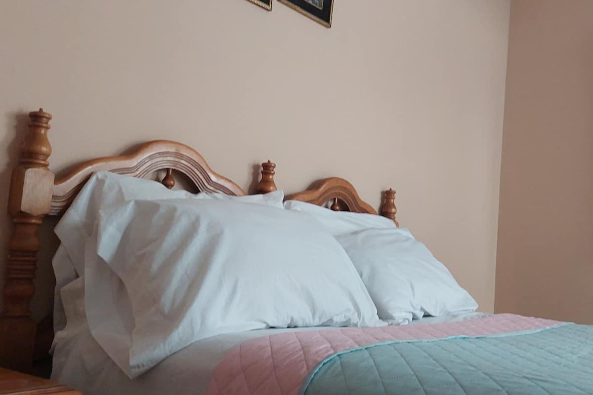 Ein Bett mit Holz Kopfteil, weißen Kissen und einer gesteppten Bettdecke.