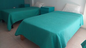 A room with two beds, each with a teal bedspread and white pillows. There are two nightstands, one with a teal drawer and the other with a white drawer. The room has white walls and a tiled floor. - Lonko Hostel Arequipa (Arequipa)